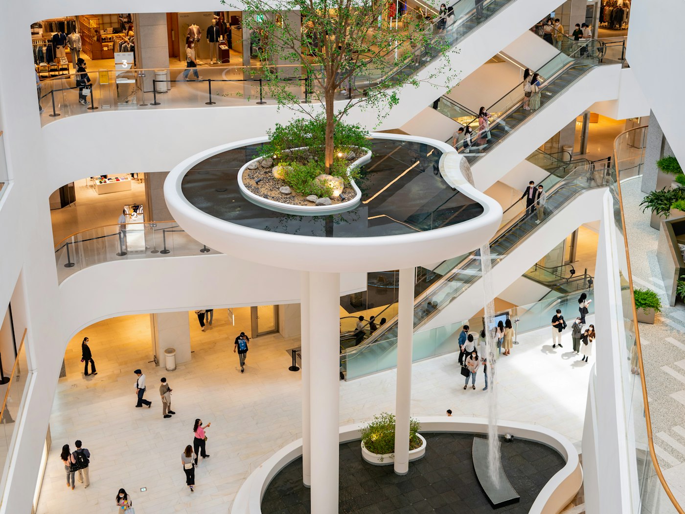 Shoppers walking through a bright Dubai mall atrium